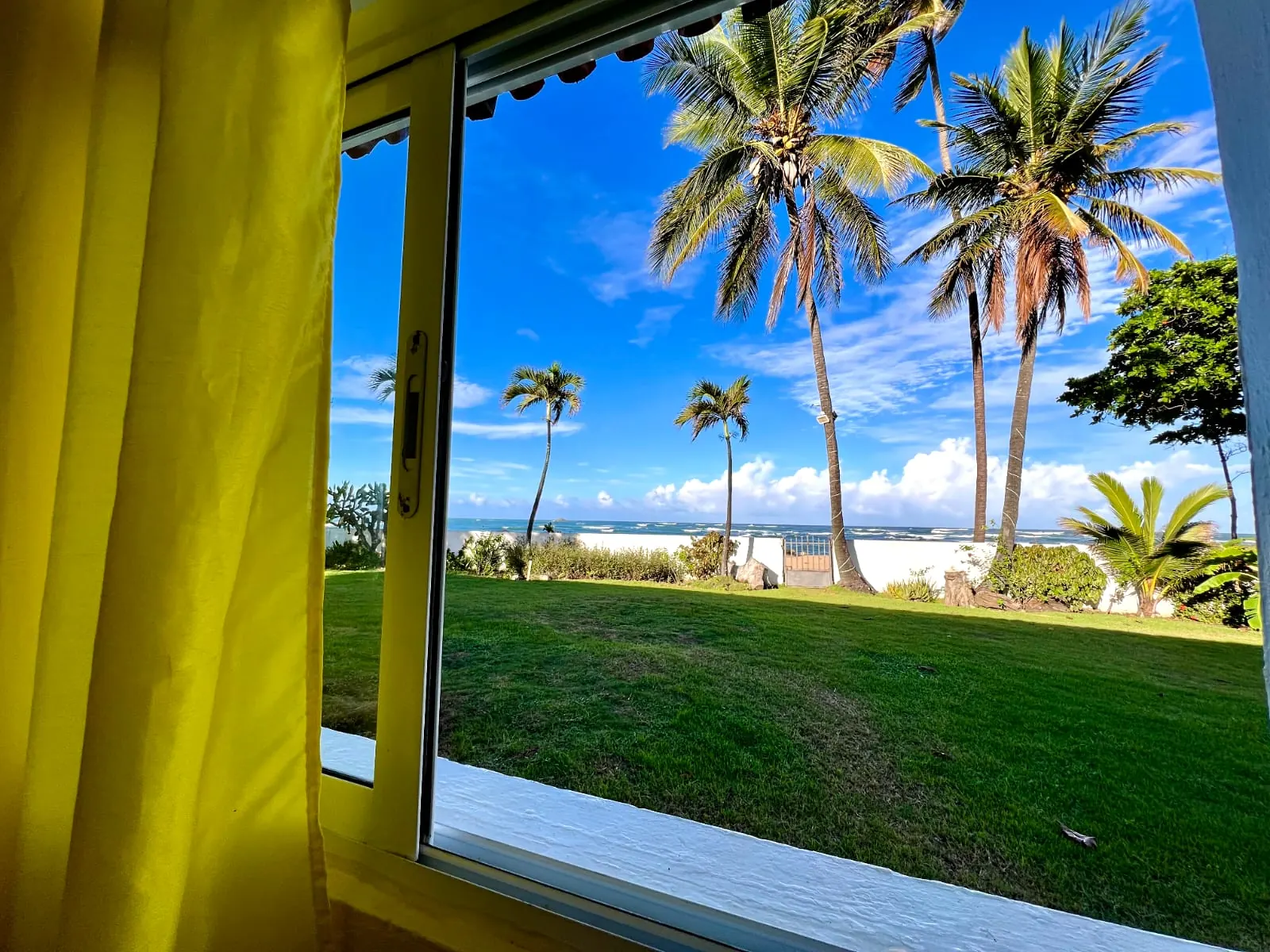 Vista desde la ventana de un dormitorio a las palmeras y el mar